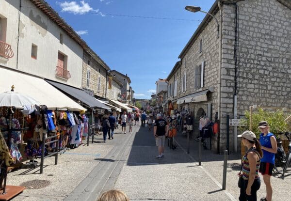 Gezellige winkelstraat met marktkramen en natuurstenen gebouwen in Ruoms, Ardèche