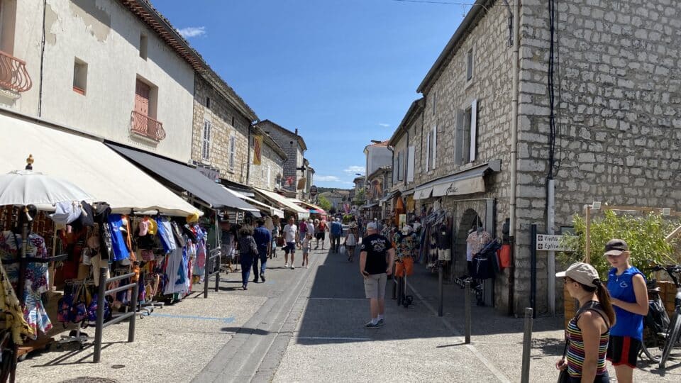 Gezellige winkelstraat met marktkramen en natuurstenen gebouwen in Ruoms, Ardèche